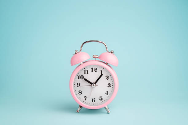 Pink alarm clock on blue background