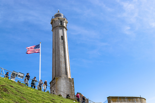 SAN FRANCISCO, USA - FEBRUARY 25, 2017: Lighthouse on Alcatraz Island against the blue sky in San Francisco, California and with tourists taking photos.