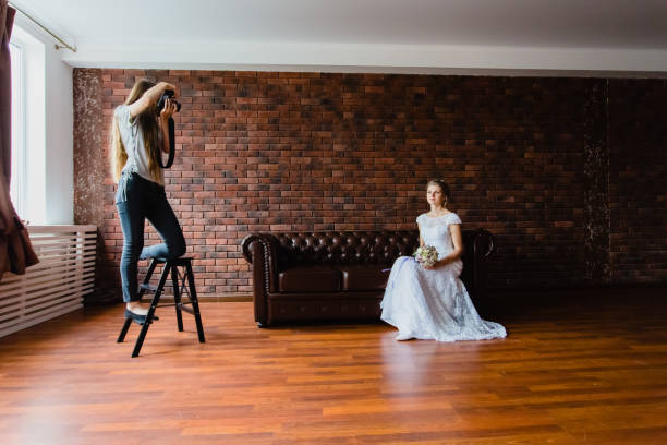 Photographer taking pictures the bride in the studio on a large leather sofa stock photo