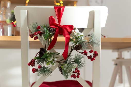 cozy decorated with Christmas decorations with red ribbon and fir branches white kitchen chair wooden. new year 2019