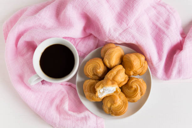 A cup of coffee with profiteroles. White background. Morning coffee. Tender composition with coffee