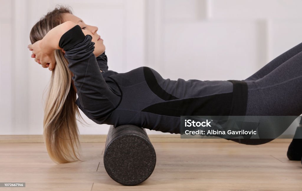 Mindful workout holistic health care. Woman doing foam roller exercises to relieve back pain Foam - Material Stock Photo