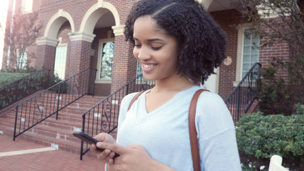 istock Young, college student smiles down at her phone 1072675752