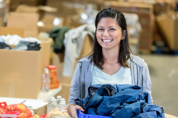 istock Young female holds a crate of clothing while smiling 1072676754