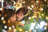 母とのクリスマス ライトと遊ぶ少年