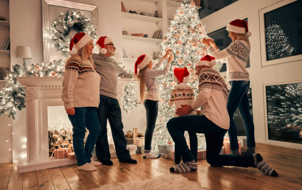 la famille heureuse au chapeau rouge, décorer le sapin de noël - christmas ball christmas ornament human hand photos et images de collection