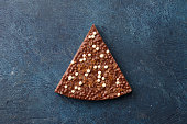 Piece of milk chocolate with rice balls and flakes on blue background