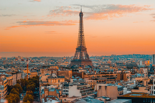 Breathtaking view of the Eiffel Tower and the serene Paris skyline during a vibrant European sunset, captured from the top of the Arc de Triomphe.