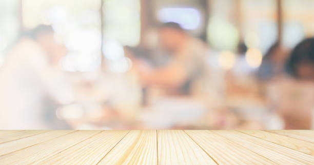 istock Empty Wood table top with Restaurant cafe or coffee shop interior with customer blur abstract vintage style bokeh light for montage product display background 1072753576