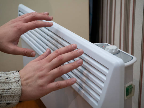 istock hands warm up at home electric heater 1072758802
