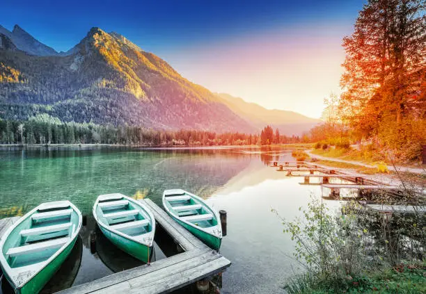 Anchored Boats on Lake Hintersee - Picturesque sunset scenery of Alpine nature in Germany, Bavaria, Europe. Autumn Landscape. Mountain peaks in backdrop, Berchtesgaden National Park, Ramsau.