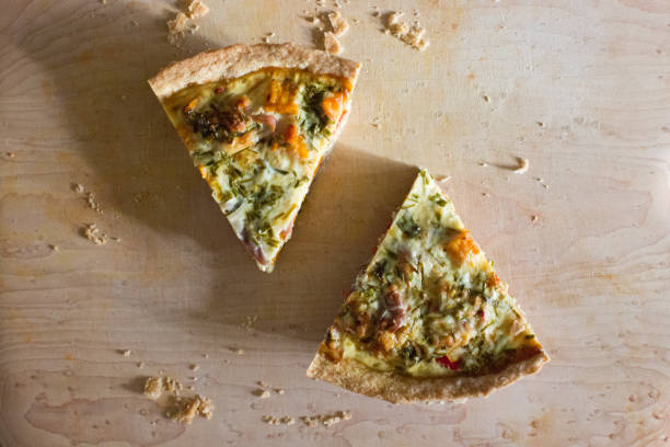 Overhead shot of two slices of cut butternut squash quiche pie on a wooden cutting broad