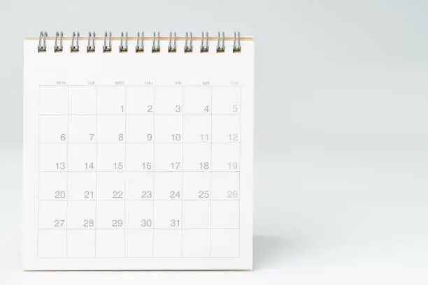 Photo of Clean white desktop calendar on white table with copy space, using for schedule appointment or year plan concept