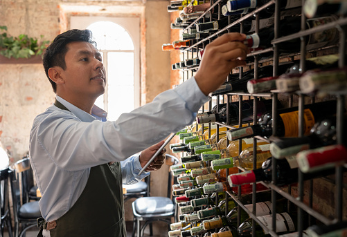 Portrait of a sommelier making an inventory at a wine cellar using a tablet computer