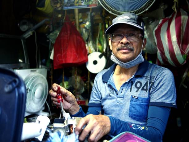 eletricista reparos um item doméstico na loja ao longo de uma rua movimentada. - street stall - fotografias e filmes do acervo