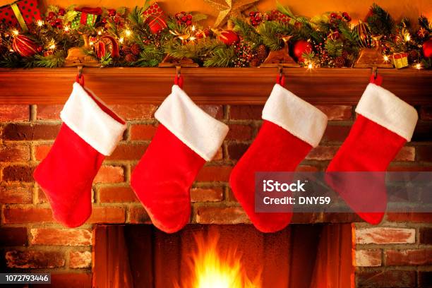 Stockings Hanging From Christmas Mantelpiece Above Roaring Fireplace Stock Photo - Download Image Now