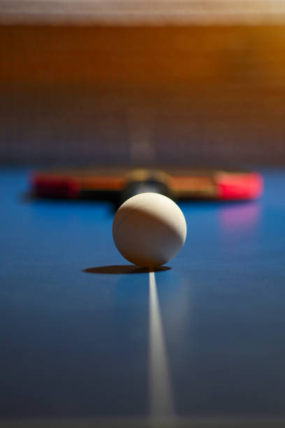 pallina da ping pong sulla linea bianca del tavolo blu e racchetta sfocata sullo sfondo - table tennis table tennis racket racket sport ball foto e immagini stock