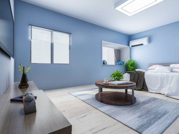 istock Spacious and unmanned bedroom design with solid wood custom closet and double bed in the blue walls, coffee table and decorations in front of the bed, TV, etc., green plants in the room 1072836324