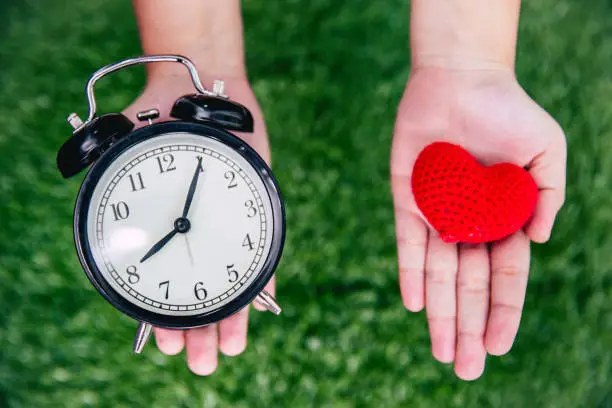 Photo of giving love times heart and clock on girl hand.