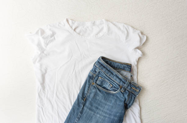 Plain white t-shirt and blue jeans on bed from above