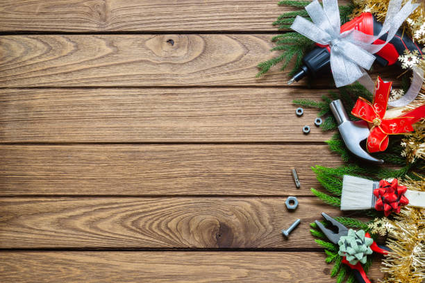 istock Merry Christmas and Happy new year handy construction tools background concept. Hammer, wrenches, screwdriver, pliers, paint brush, bows decoration on  wood background. Top view with copy space. 1072874282