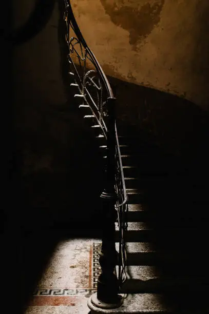 Photo of A top view of the spiral staircase in the old house and a broken stone floor. Dilapidated houses, the building is abandoned, destroyed, in the old town of Tbilisi, Georgia.