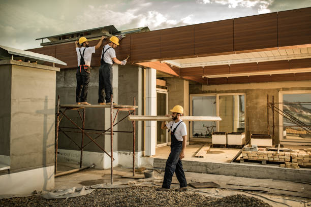 Construction engineer with house building plans against the unfinished residential house