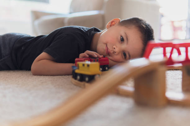 istock Little boy lying down and playing with a wooden train set 1072914392