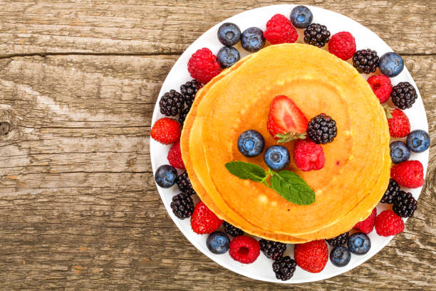 istock Pancakes stack with different berries on old wooden background with copy space for your text. Top view. Flat lay 1072929726