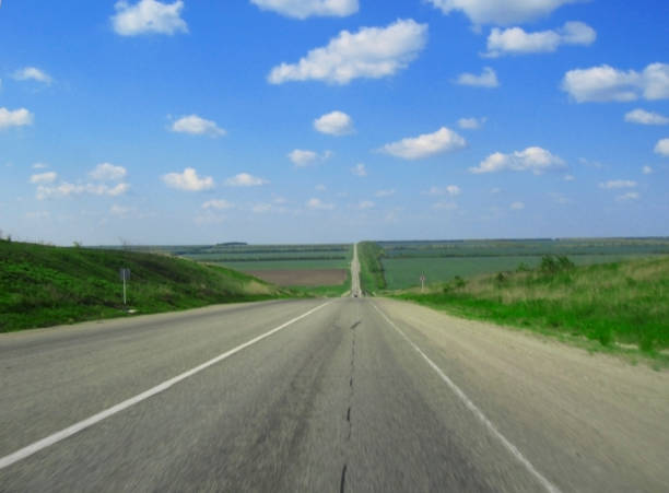 istock Wide highway and meadow. Clouds over and blue sky 1072933792