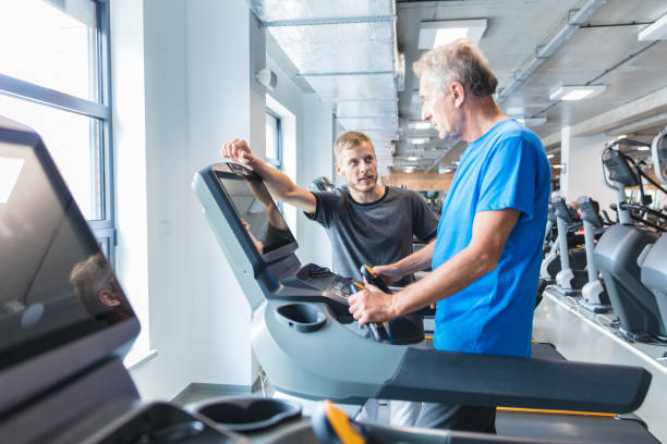 istock Senior man with trainer exercising on treadmill 1072943980