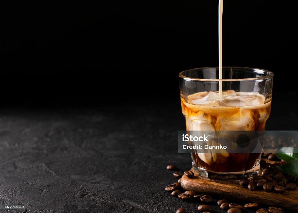 vidrio frío colar el café con hielo y leche sobre fondo negro u oscuro - Foto de stock de Café - Bebida libre de derechos