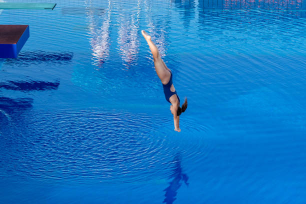 молодая женщина ныряет в бассейн - skill side view jumping mid air стоковые фото и изображения