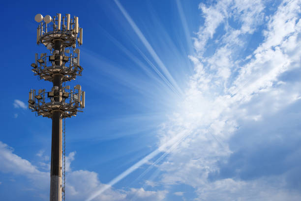 Telecommunications antenna tower for radio, television and telephony on blue sky with clouds and sun rays