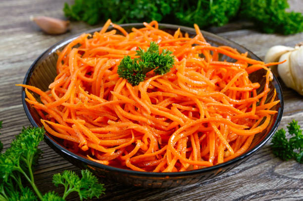 salads from fresh carrots. korean spicy vegetables salad in bowl on a wooden table. vitamin menu. vegan cuisine. - carotene imagens e fotografias de stock