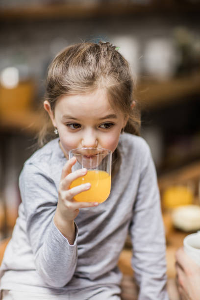 istock Little girl drinking fresh orange juice. 1072958548