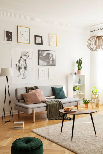 istock Posters above settee with pillows in bright living room interior with pouf next to table. Real photo 1072959622