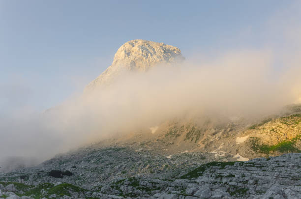 Fog rolling over mountain during sunset stock photo