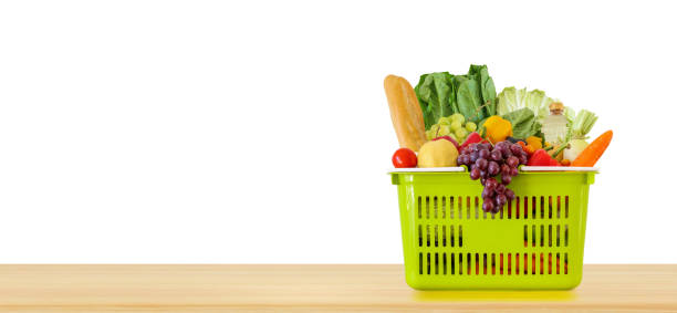 fresh fruits and vegetables grocery product in green shopping basket on wood table top isolated on white background - shopping basket imagens e fotografias de stock