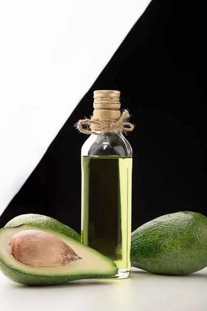 Natural avocado oil for cooking. Three fresh tropical fruit avocado, cut on a white table. It is black and white background