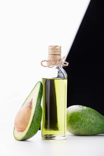 Natural avocado oil for cooking. Three fresh tropical fruit avocado, cut on a white table. It is black and white background