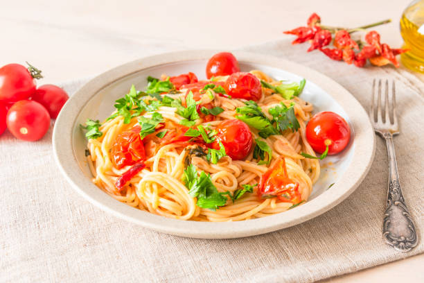 istock Pasta al pomodoro - spaghetti with cherry tomatoes and parsley on a plate close up in a rustic style 1072979120