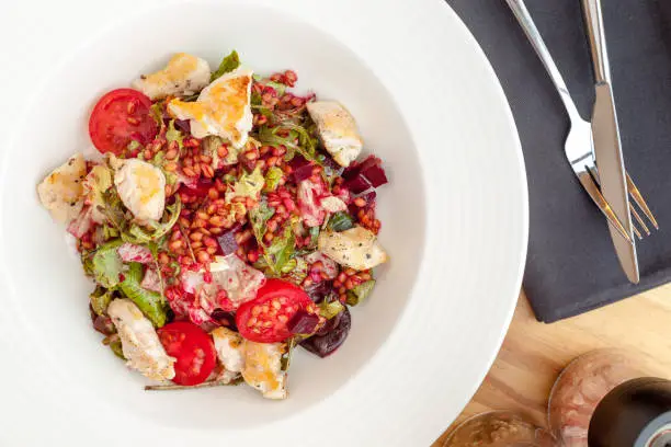 Hot chicken salad with einkorn, salad mix, red beetroot and cherry tomatoes.