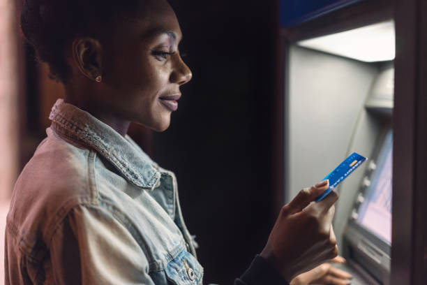 mulher feliz usando o atm na rua da cidade - currency spending money african descent black - fotografias e filmes do acervo