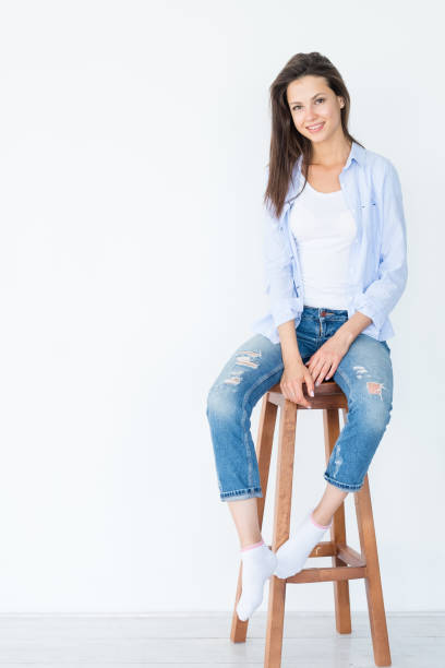 istock smiling woman sit stool white background casual 1072994608