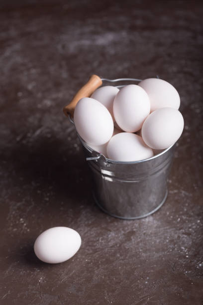istock White chicken eggs in bucket on the dark background 1072994648