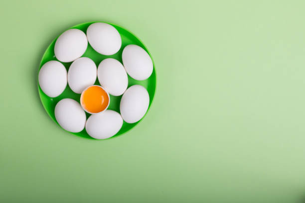 istock White eggs and egg yolk on the green background 1072994744