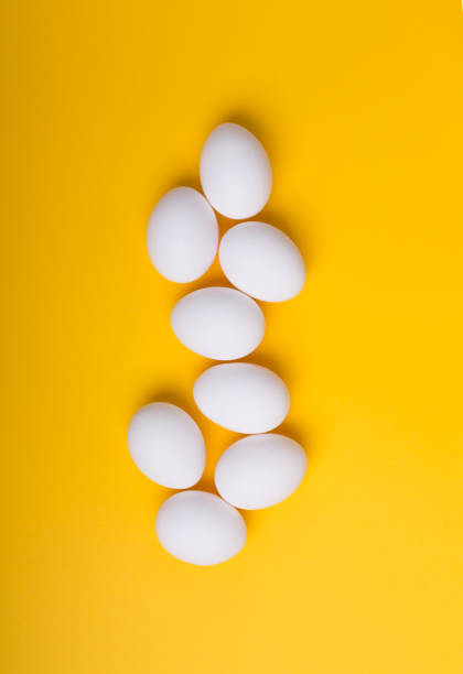 istock White eggs on the yellow background. Vertical orientation 1072994800