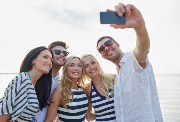 istock happy friends on beach and taking selfie 1072996934