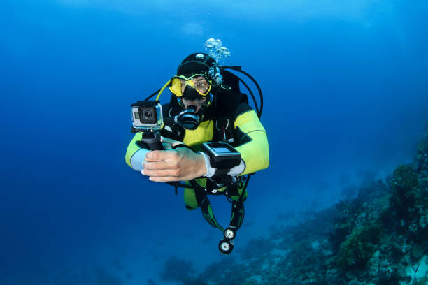 Scuba diver using a GoPro while diving underwater Male scuba diver using an action camera to take some underwater shots. deep sea diving underwater underwater diving scuba diving stock pictures, royalty-free photos & images